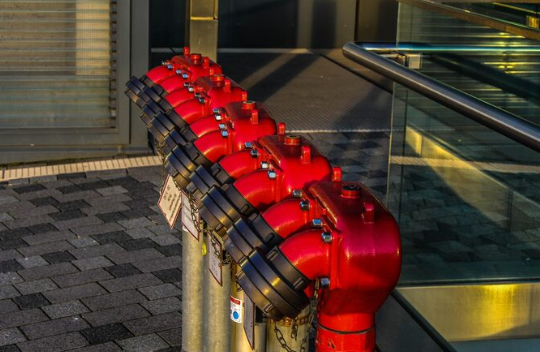 Red firefighting pipe connections mounted outdoors.